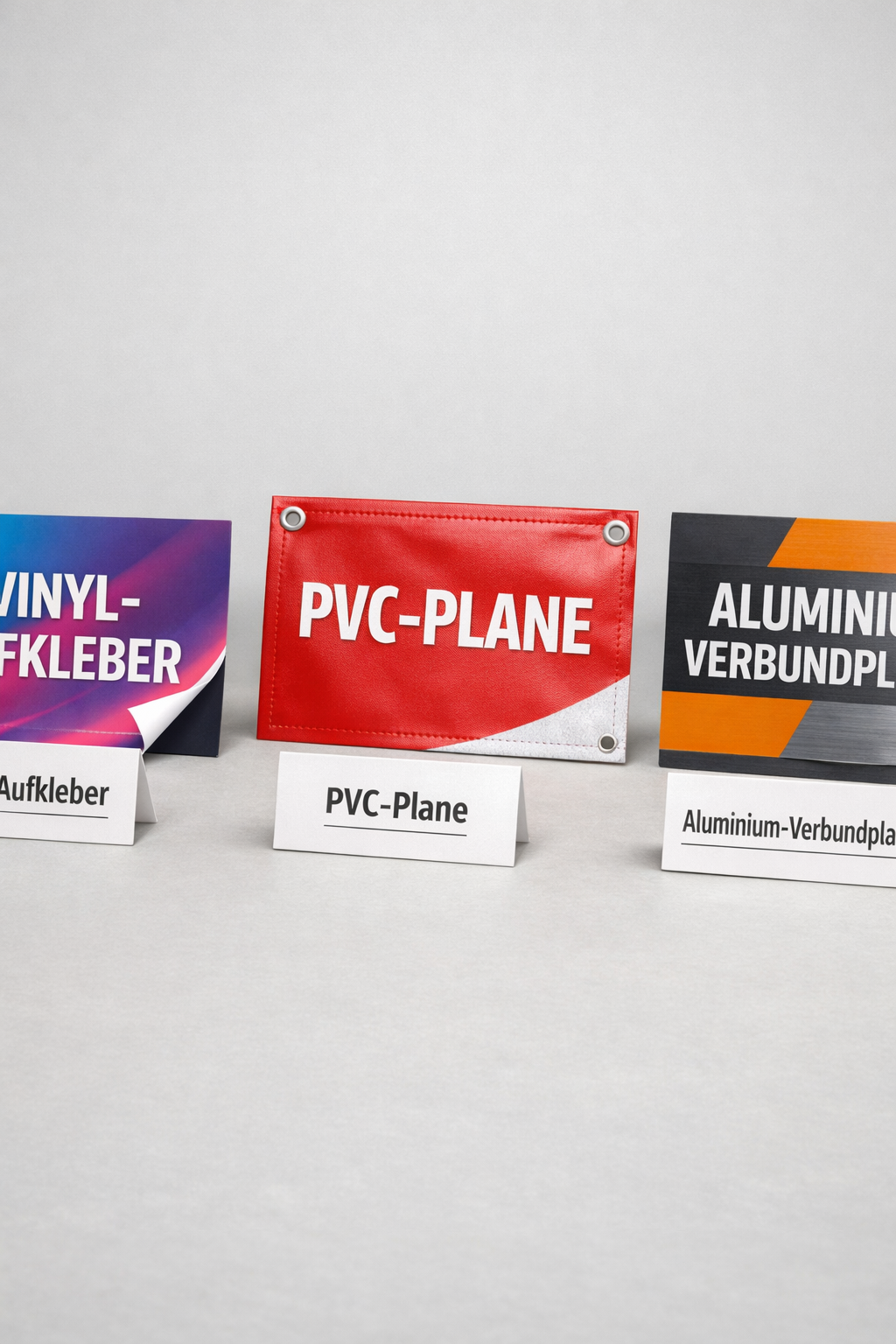 () close-up product comparison scene showing three different Messebeschriftung material samples side by side on a light grey