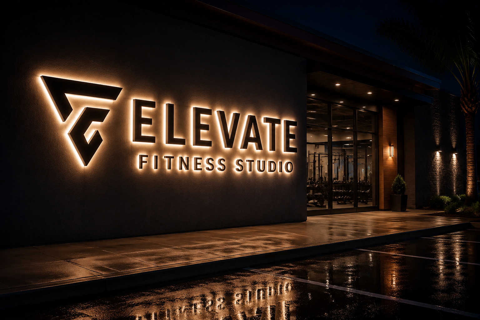 Fitness studio storefront at night with halo-lit dimensional letters glowing against a dark facade, light spill on the wet pavement below, entrance visible to the side